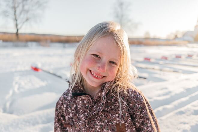 雪原を背景にこちらをみて笑う少女